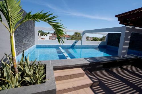 una piscina con una palmera junto a una casa en Sophie Hotel Boutique, en Santa Cruz Huatulco