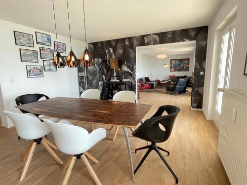 a dining room with a wooden table and white chairs at SUNSET Apartment direkt am Bodensee mit Parkplatz in Lochau