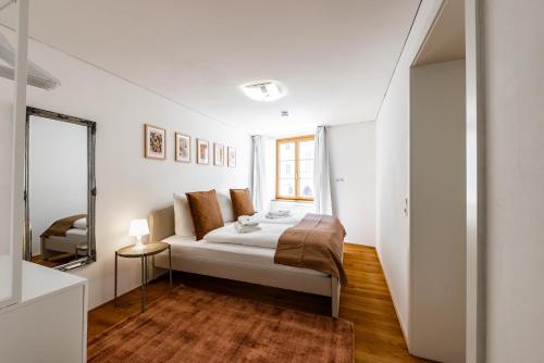 a white bedroom with a bed and a mirror at City Apartment DOWNTOWN in Bregenz