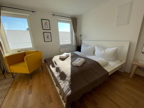 1 dormitorio con 1 cama con silla amarilla y 2 ventanas en Maurerhaus Studio, Top 5, en Hohenweiler