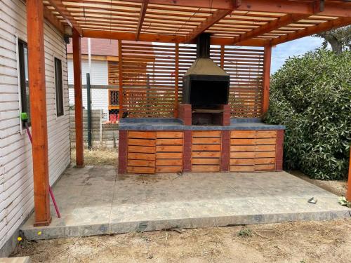 a patio with an outdoor grill under a wooden pergola at Casa En Papudo Lomas del Mar in Papudo