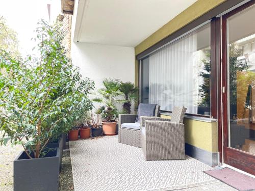 patio z dwoma wiklinowymi krzesłami i roślinami doniczkowymi w obiekcie Stylische Wohnung mitten in der Stadt Bregenz w Bregencji