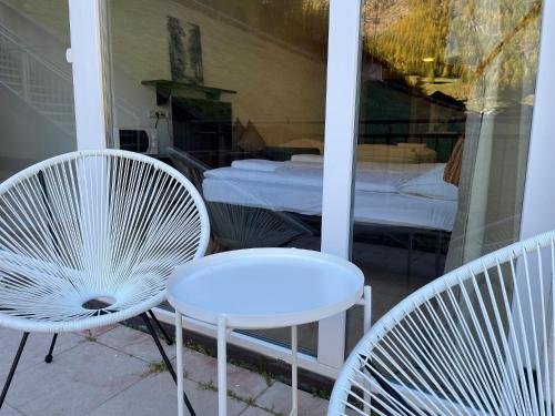 - deux chaises blanches et une table sur une terrasse couverte dans l'établissement International House Sölden Studio-Apartment ZW 6, à Sölden