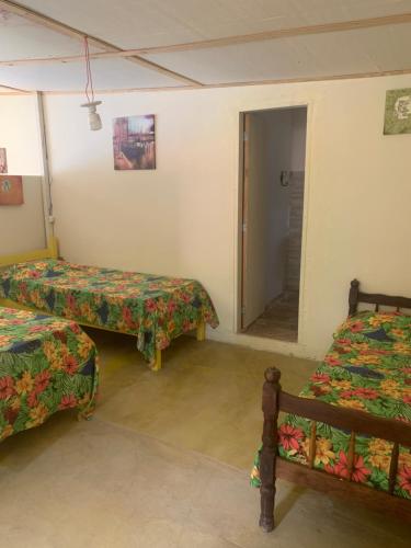 a room with two beds and a door to a bathroom at Aldeia Gaia Chalés in Teresópolis