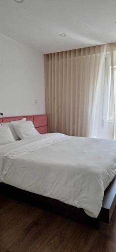 a bedroom with a large white bed with a window at Apartamento T3 - férias in Barcelos
