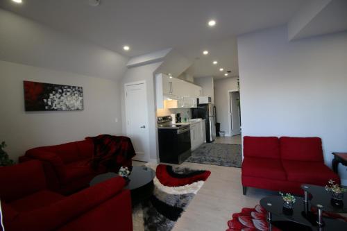a living room with two red couches and a kitchen at Feel at home in Chestermere in Chestermere
