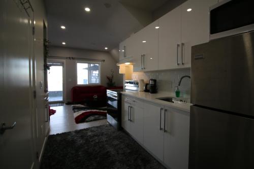 a kitchen with white cabinets and a black refrigerator at Feel at home in Chestermere in Chestermere