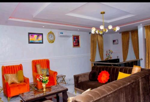 ein Wohnzimmer mit einem Sofa und 2 Stühlen in der Unterkunft Motalvin Court in Lagos