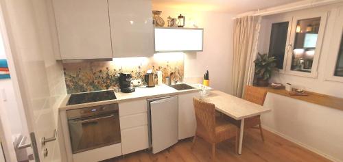 a kitchen with white cabinets and a table and a sink at Stilvoll Gertrud Schlössli 1 Zi Studio in St. Gallen