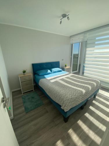 Un dormitorio con una cama azul y una ventana en Depto nuevo en brisas del sol en Talcahuano