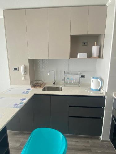 a small kitchen with a sink and a blue stool at Depto nuevo en brisas del sol in Talcahuano