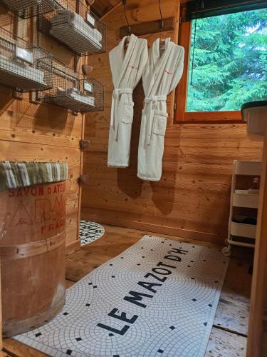 une cabine avec des vêtements blancs suspendus à une fenêtre dans l'établissement Le mazot d'H, à Entremont