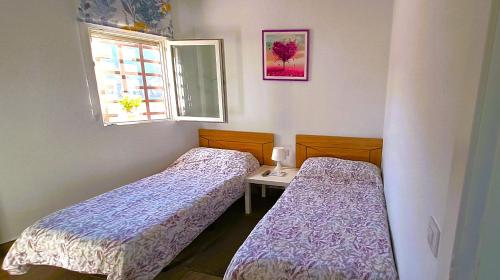 2 camas en una habitación pequeña con ventana en Posada de Bien, en Herencia