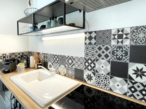- une cuisine avec du carrelage noir et blanc sur le mur dans l'établissement Lapin Blanc - Joli studio avec terrasse, à Marseille