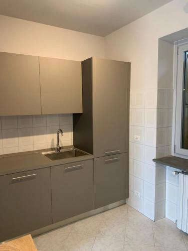 a kitchen with gray cabinets and a sink at 123 Guest House in Alba