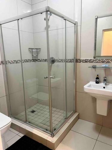 een glazen douche in een badkamer met een wastafel bij Seasons Court umhlanga 2bed Apt in Durban
