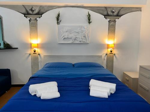 a blue bed with two white towels on it at Nel Pieno Centro Storico [Tutto a Due Passi] in Casale Monferrato