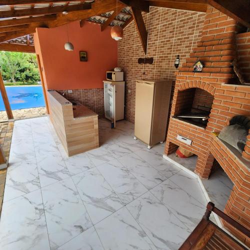 a kitchen with a brick wall and a brick oven at Chácara dos Cunha - Atibaia in Atibaia