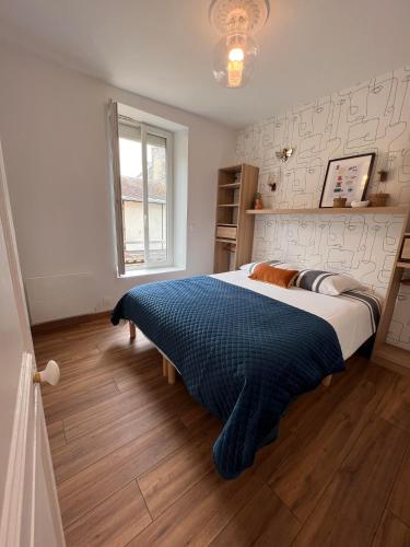une chambre avec un grand lit avec une couverture bleue dans l'établissement En plein coeur d'Arromanches - Coté Ponton, à Arromanches-les-Bains