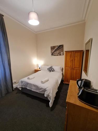 a bedroom with a bed and a dresser in it at Cathcart Place Rooms in Edinburgh