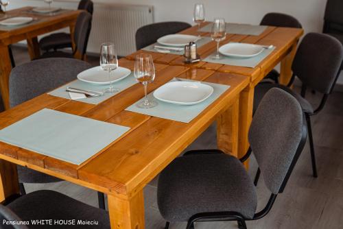 a wooden table with plates and wine glasses on it at White House Moieciu in Moieciu de Jos