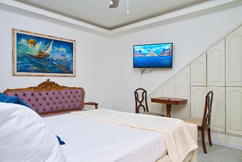 a bedroom with a bed and a table and a tv at Hotel Boutique Fiorentina Medellín in Medellín