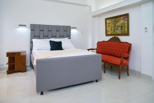 a bedroom with a bed and a red chair at Hotel Boutique Fiorentina Medellín in Medellín