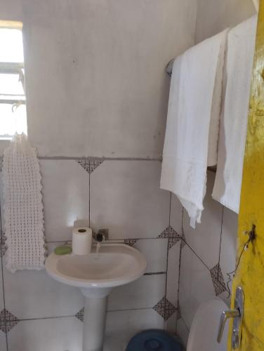 a bathroom with a sink and a toilet and towels at Pousada 4 estações/chalés in Sapopema