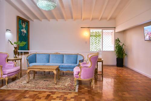 a living room with a blue couch and pink chairs at Hotel Boutique Fiorentina Medellín in Medellín