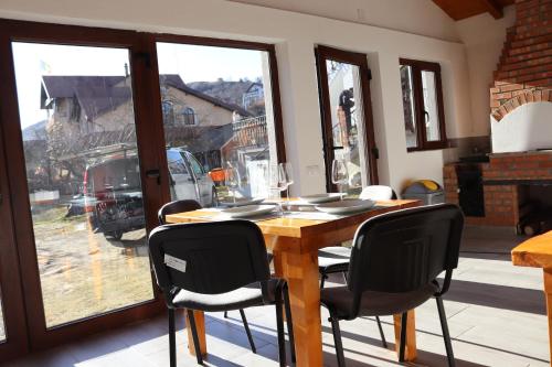 a dining room table with black chairs and a large window at White House Moieciu in Moieciu de Jos