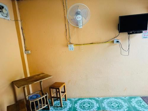 a room with a fan and a table and stool at Bansuan Resort, Long, Phrae in Long