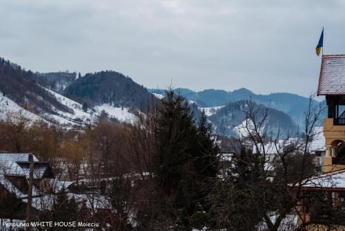 a snow covered mountain in a town with a building at White House Moieciu in Moieciu de Jos