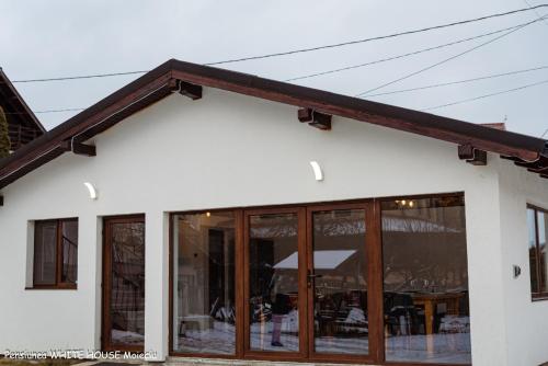 a white building with windows and a roof at White House Moieciu in Moieciu de Jos