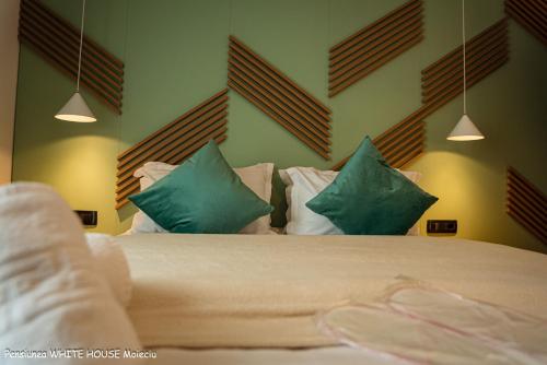 a bedroom with a bed with green and white pillows at White House Moieciu in Moieciu de Jos