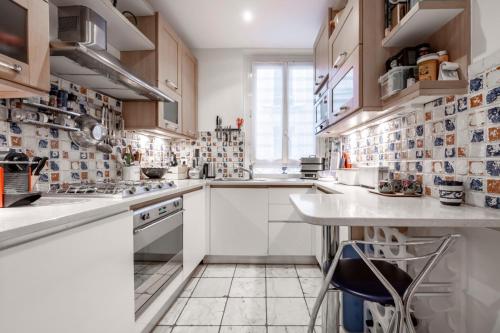 une cuisine avec des armoires blanches et un comptoir dans l'établissement Veeve - Mindful Enlightenment, à Paris