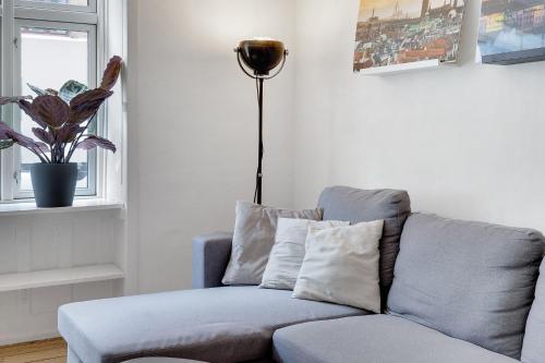 een woonkamer met een blauwe bank en een lamp bij Perfectly located cozy apartment in Kopenhagen