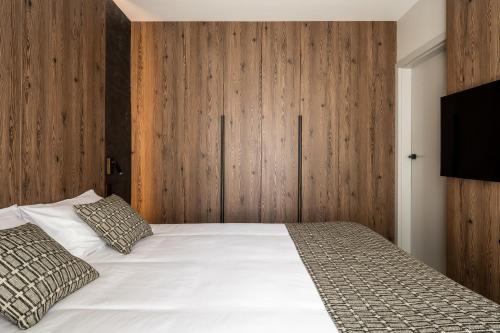 a bedroom with a white bed and wooden walls at Apartamenty Podhale in Zakopane