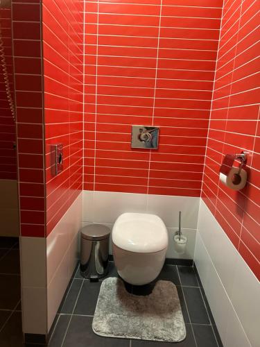 a red tiled bathroom with a toilet and a rug at AR GOLDEN HOUSE in Košice