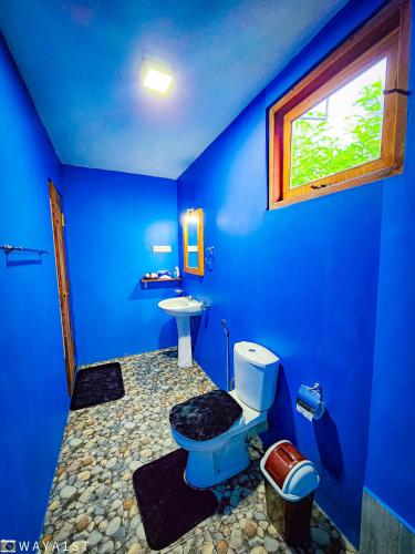 a blue bathroom with a toilet and a sink at Bright Sun Safari in Udawalawe