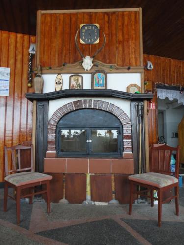 una chimenea con 2 sillas y un reloj encima en Семеен хотел Узана, en Gabrovo
