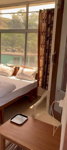 a room with two beds and a window and a table at haridwar jmg and kedarnath Hotel in Haridwār