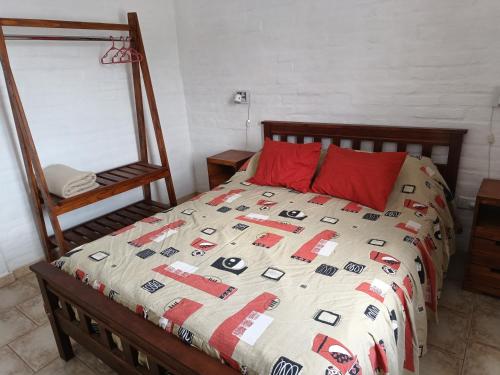 een bed met een dekbed met een rood kussen en een spiegel bij Las Madreselvas in Villa de la Quebrada