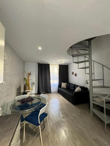 a living room with a glass table and a spiral staircase at El Cortijo Bungallows in Playa de las Americas