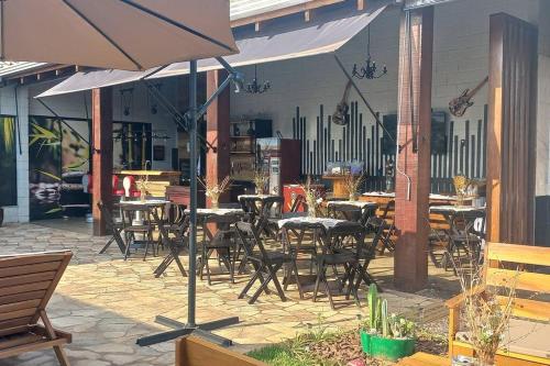 un patio con mesas, sillas y una sombrilla en recanto do sossego., en Sinop