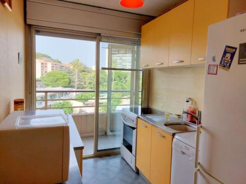 une cuisine avec un réfrigérateur blanc et une fenêtre dans l'établissement Bocca Baie T2 en bord de mer - Axelle Loc Appart, à Cannes