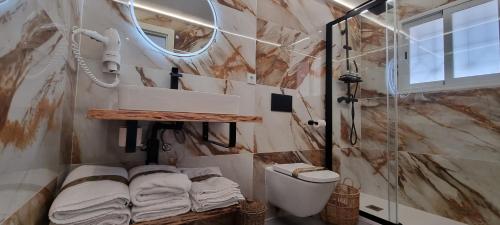 a bathroom with a shower and a toilet and towels at Principado Benidorm Suites Levante in Benidorm