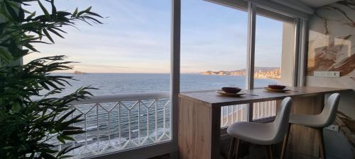 a balcony with a table and chairs and a view of the ocean at Principado Benidorm Suites Levante in Benidorm