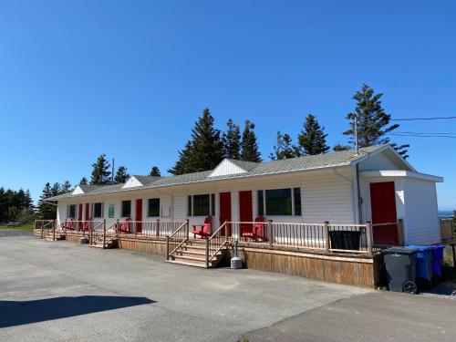 a white house with red doors on a lot at Maison LeBreux - Motel in Petite-Vallée