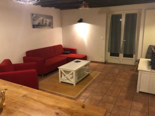 un salon avec un canapé rouge et une table dans l'établissement Gite aux volets bleus, à Écuelles