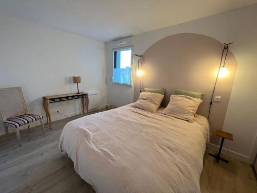 une chambre avec un grand lit blanc et une fenêtre dans l'établissement Gwiskaou A 170m de la plage, à Concarneau